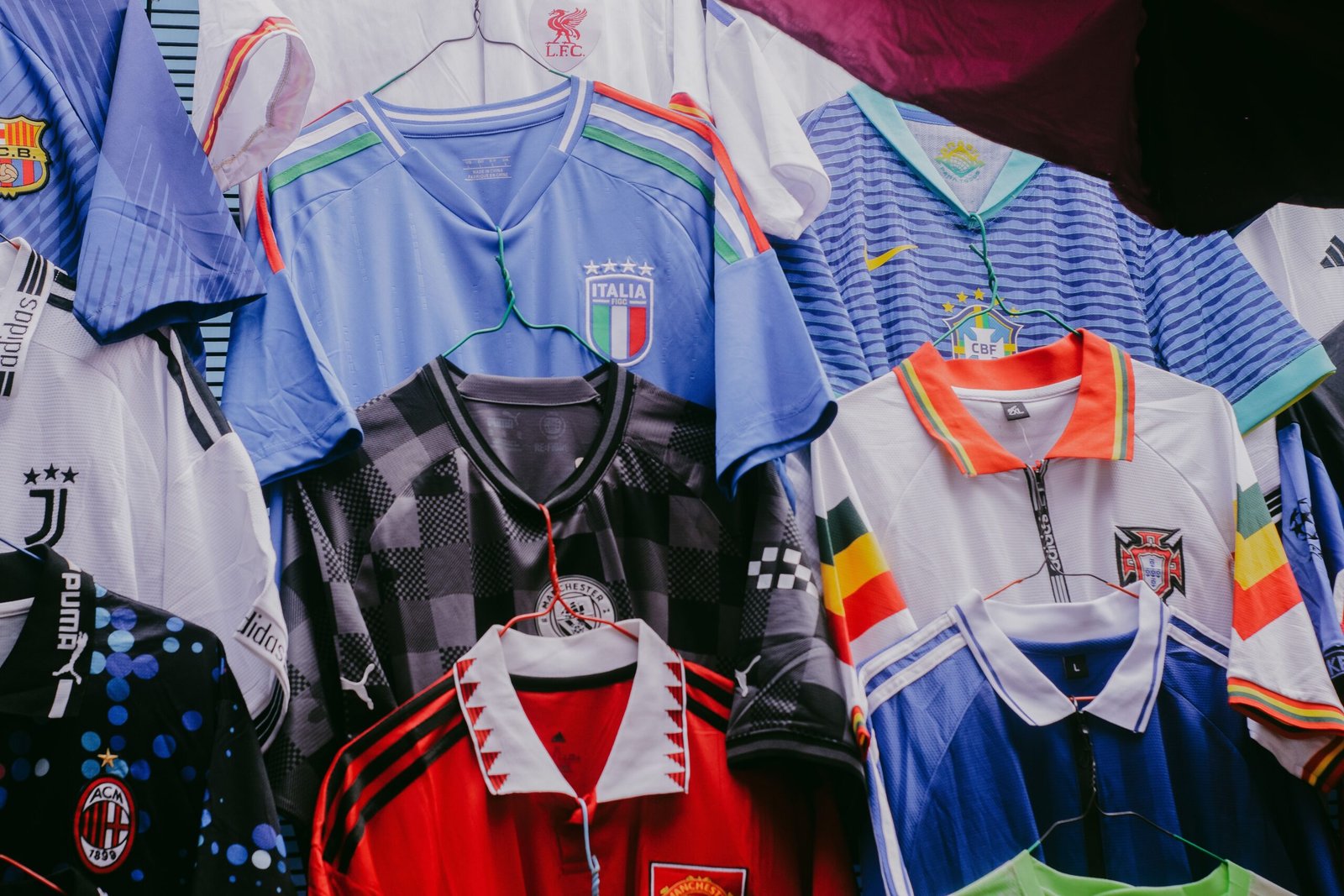 Camisetas de fútbol de distintos equipos colgadas en percha